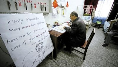 張大爺在門衛室里工作，旁邊是紅爆網絡的溫馨提示牌記者