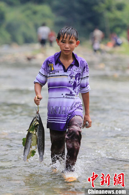 圖為7月9日，一名男孩在鬧魚節活動中抓到了兩條魚。譚凱興 攝