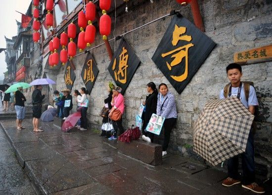 　4月29日上午11時20分，一些游客和古城當地的居民躲在一個酒吧的屋檐下避雨。這些當地居民以為游客拍照謀生，一場降雨讓他們的生意更加清淡。