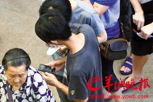 排隊的“黃牛”各手執一疊白紙，上面寫好了要掛號的人的信息，包括姓名、電話、要掛的科室等。穿黑白花紋衣服的老婆婆正在排隊掛號