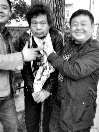 兩名接訪人員與患有癌癥的訪民段新德合影時，面帶笑容擺出勝利的手勢。