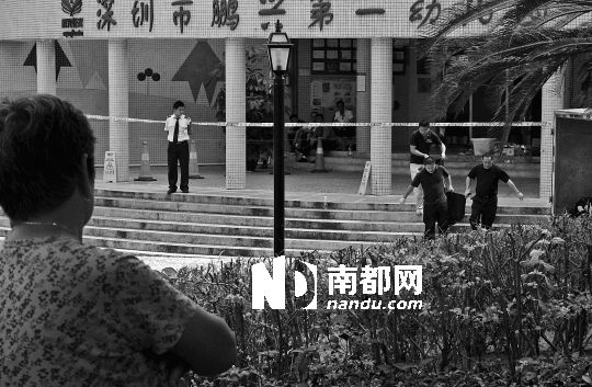 →7月19日，鵬興花園第一幼兒園門前，民警在現(xiàn)場進行完勘查取證后，園長和保安的尸體被運走。南都記者 徐文閣 攝