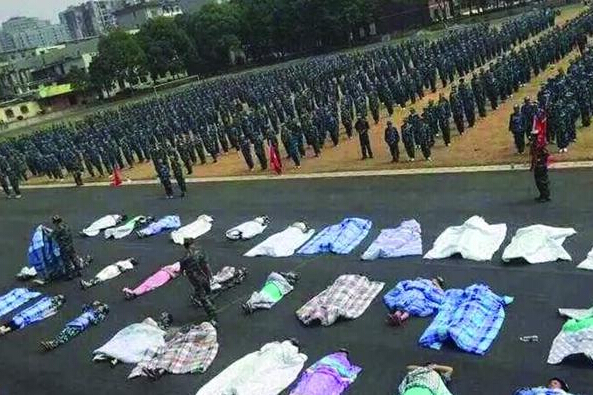 20多名女生躺在瀝青跑道上，身上嚴(yán)嚴(yán)實(shí)實(shí)地裹著棉被，接受太陽的照曬。