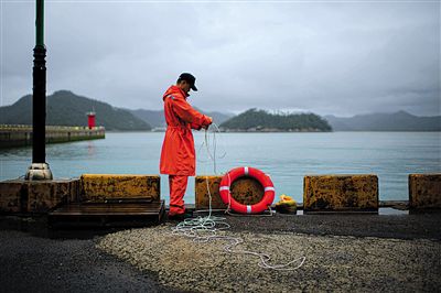 7月6日，韓國珍島，一名海岸警察在港口系救生圈。4月，客輪在珍島近海發生沉船事故后，仍有11人下落不明。