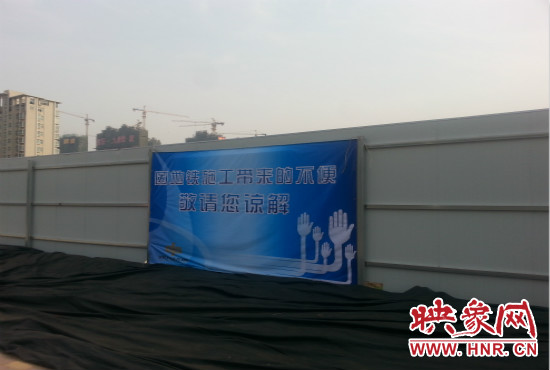 道路南側圍起了白色的圍擋，墻上標示著“因地鐵施工帶來的不便敬請您諒解”的提示牌。