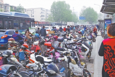 省人民醫院北門，路邊的公交站牌處停滿非機動車，上、下客只能在快車道上。