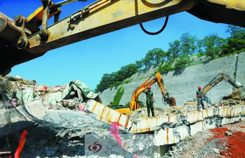 為確保道路盡早通車，工人師傅冒著烈日，指揮施工機械清理爆破現場