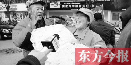 一名環衛工師傅高興地從孫德坤手里接過棉被