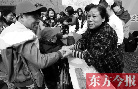 昨日，鄭大四附院的大樓前，“面人鄭”鄭玉芬（右）向前來捐款的殘疾人表示感謝