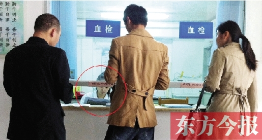 昨日，鄭州市二七區疾控中心辦證大廳，血檢窗口內一名女工作人員，邊接受辦證者咨詢邊看報紙