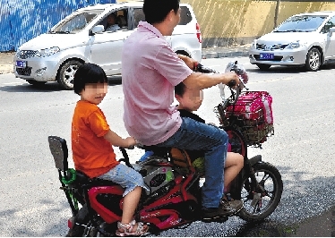 周先生騎著一輛低矮的電動(dòng)車帶著一對(duì)兒女，很不安全。