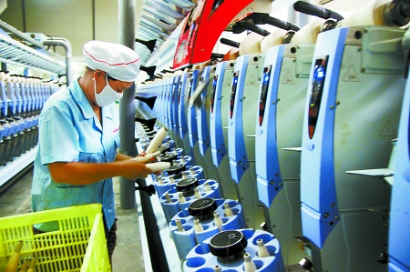 7月3日，在鄧州市永泰棉紡有限公司電腦控制全自動紡紗車間，紡織工人正在生產棉紗。