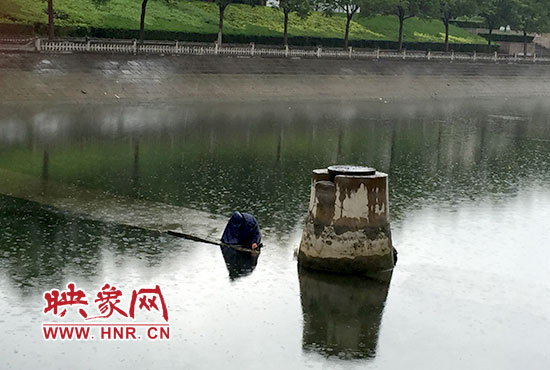 一女子穿著雨披獨自站在東風渠中