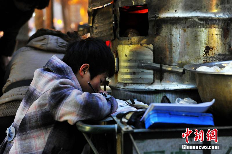 男孩西安路燈下寫作業 媽媽邊賣紅薯邊輔導