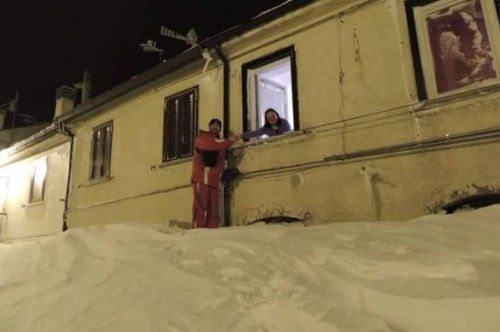 一個居民站在積雪上，可以與一名二樓鄰居在窗口握手。（來源：意大利氣象局）