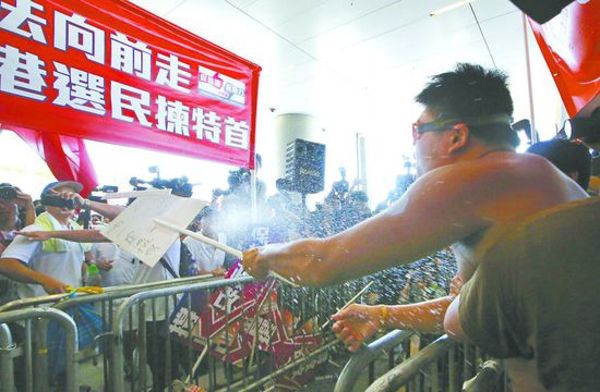 17日，在香港立法會外，一名反對政改的男子向支持派人群投擲標(biāo)牌。