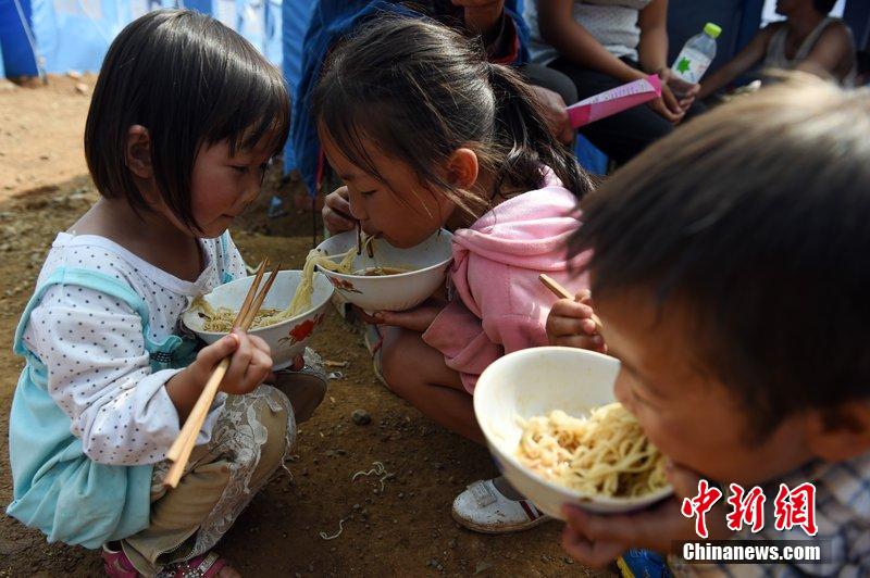 2014年8月6日，云南魯甸龍頭山災區，兒童在帳篷外吃飯。