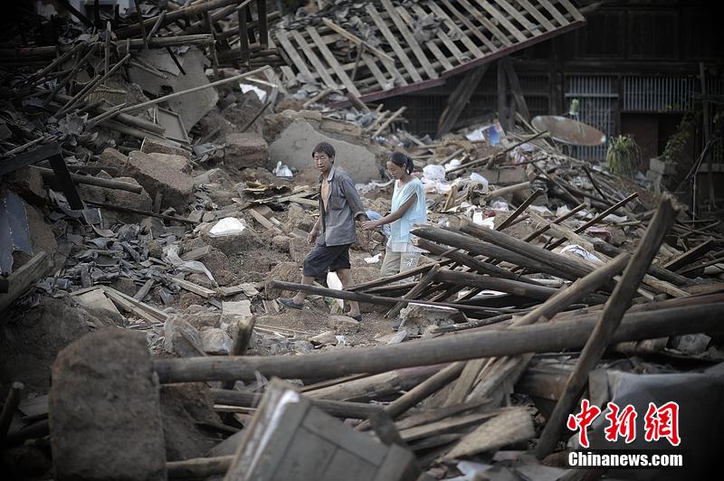 2014年8月5日，云南昭通龍頭山鎮老街，一對夫妻從居住房屋的廢墟中走過。