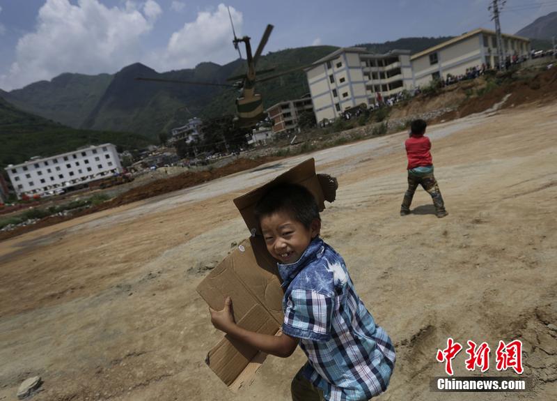 云南省昭通市魯甸縣發生6.5級地震。幾個孩子在直升機降落的平地上玩耍。
