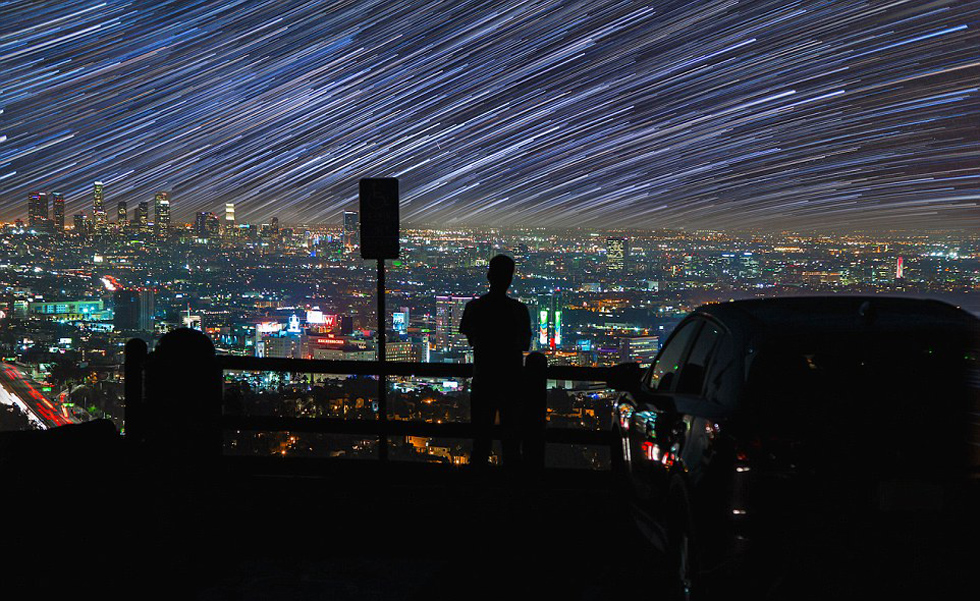 照片中，一名男子看著流星和隕星劃過天空。（網頁截圖）