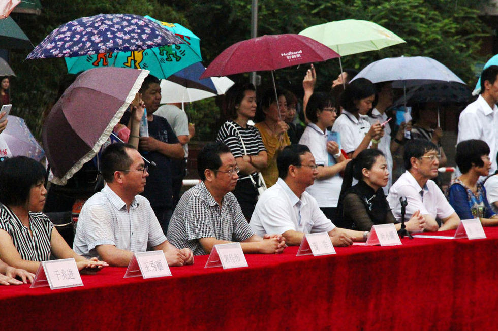 在主席臺上觀看的校領導也堅持不打傘陪學生一起淋雨，身旁站滿了打傘觀看的家長。