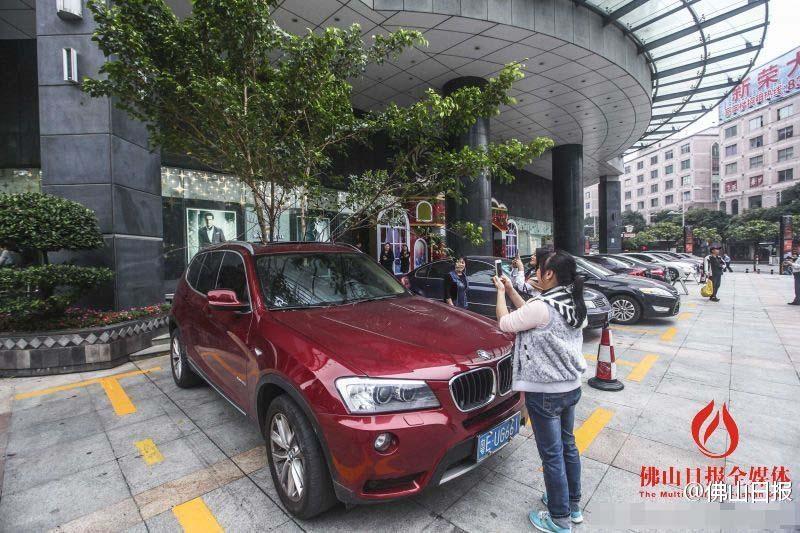 一輛停在停車位上的寶馬轎車，被墜落的樹枝砸中，樹枝徑直插入車內，現場引發不少市民圍觀拍照。