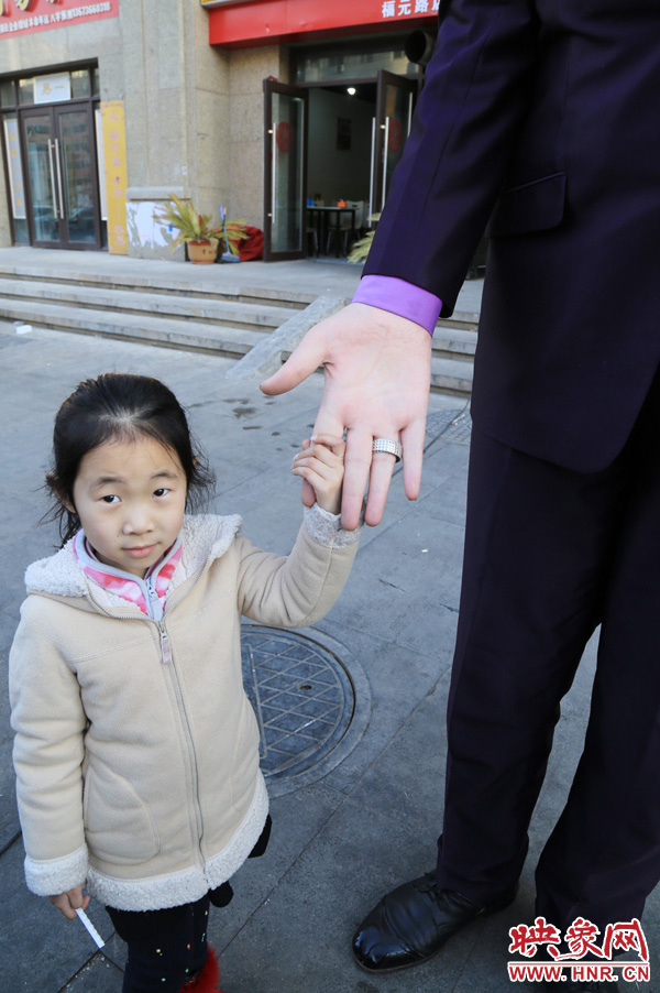 巨人“張歡”牽著一名漂亮的小女孩，兩人的手大小對比非常明顯。